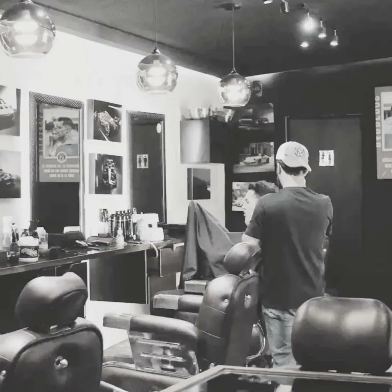Barbero atendiendo a un cliente en una barbería en blanco y negro