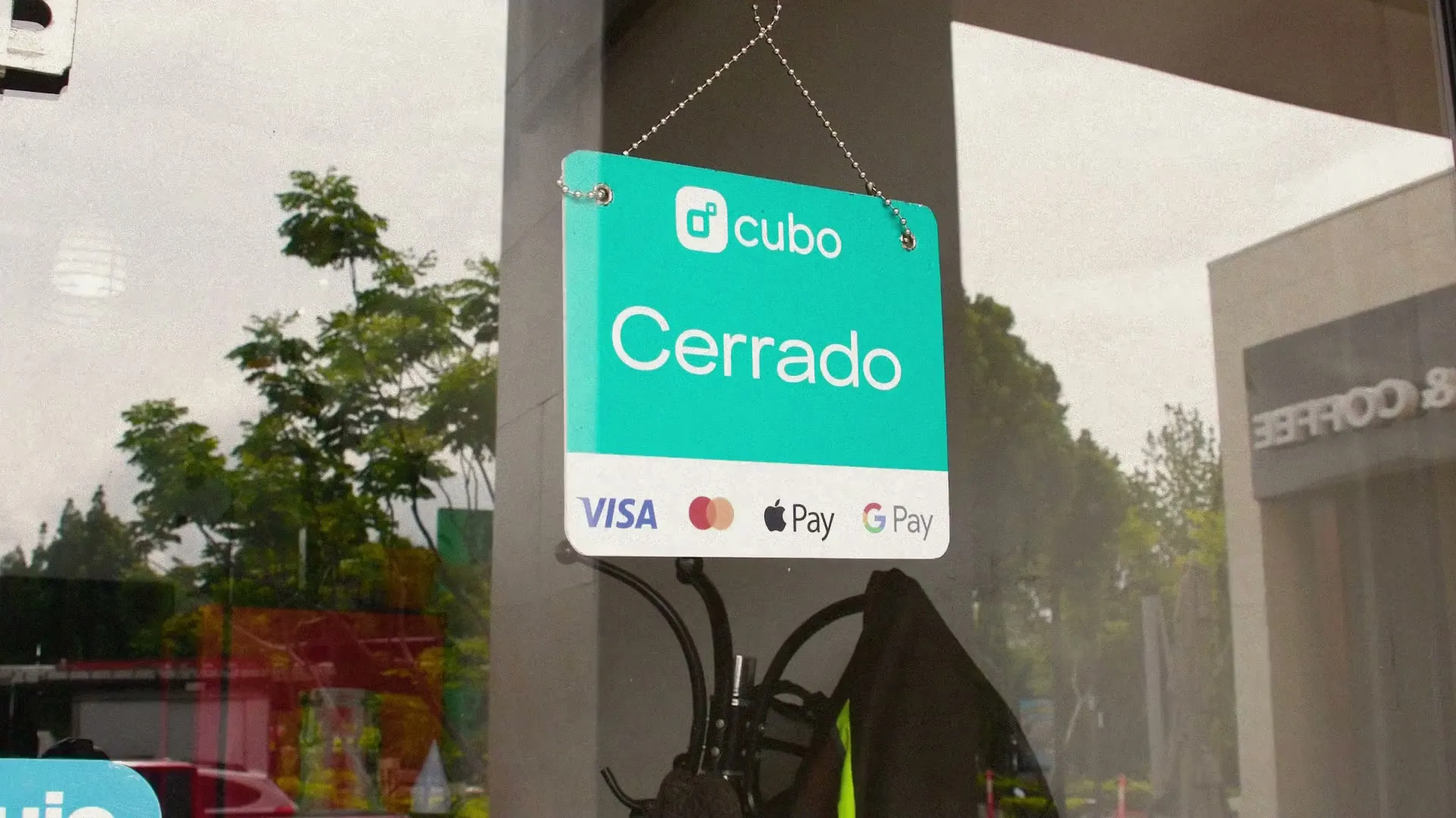 Letrero de Cubo con la palabra Cerrado colgado en la puerta de vidrio de un negocio