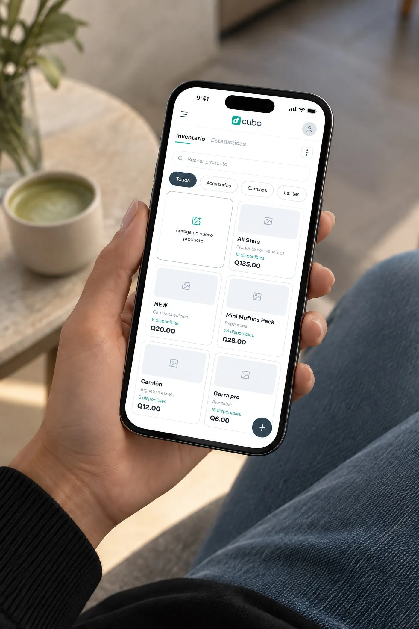 Una mano sostiene un celular con el inventario de productos de Cubo con precios en quetzales