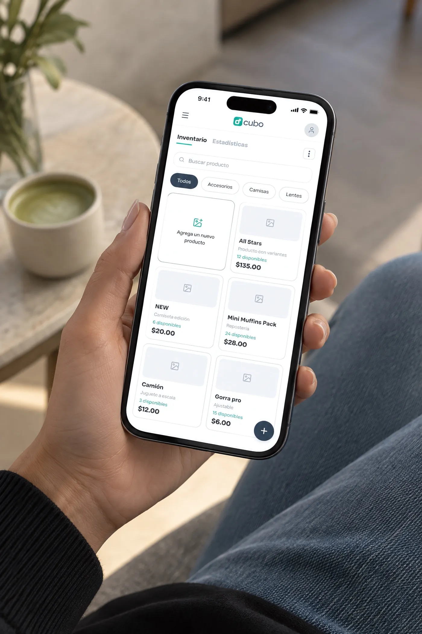 Una mano sostiene un celular con el inventario de productos de Cubo